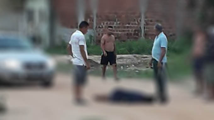   Moradores observam o corpo deixado pelos assassinos no meio da rua; Vítima foi morta com tiros na nuca
