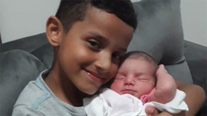   Pedro Henrique, de 8 anos, segura a irmã Maria Eduarda, de 26 dias, após ter conseguido, junto com a mãe, acionar o SAMU a tempo de salva-la de engasgo