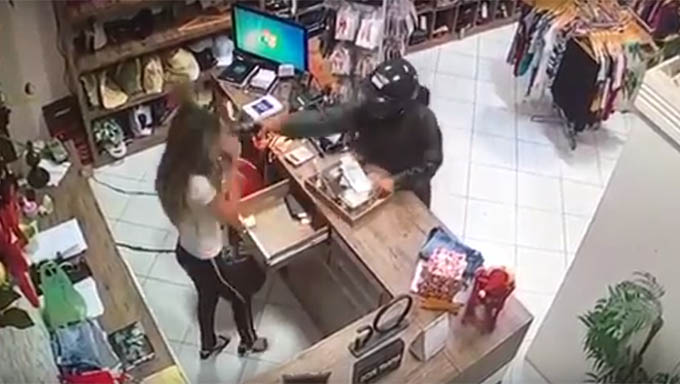 Imagem 1 -  Após a vendedora Renata Raniele esvaziar o caixa, o bandido estende a mão e atira com o cano do revólver bem perto do rosto da vítima, no que a policia chama de tiro à queima roupa