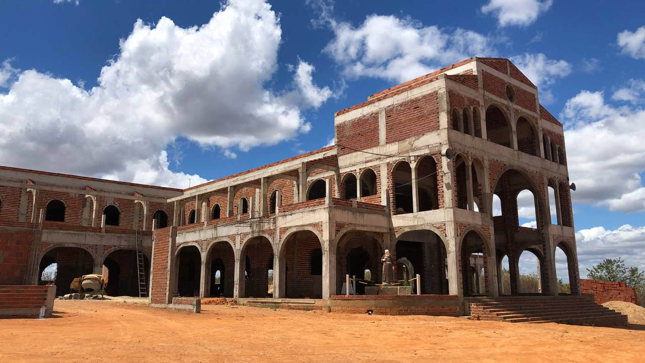 Imagem 1 -  O templo está sendo construído em um terreno de 10,8 hectares, doado por uma devota de São Miguel. A obra foi iniciada em 2016 e vem sendo totalmente realizada com doações de fiéis. Atualmente o local já está coberto e serão iniciadas as obras do piso. A previsão é que seja concluído nos próximos 4 anos. De acordo com o historiador Renê Guida, que acompanhou a equipe do Mossoró Hoje nesta visita, missas já estão sendo realizadas nos domingos, no local da construção, atraindo fiéis de diversas cidades da região. A expectativa é que o memorial se torne um santuário, após a canonização do Frei Damião.