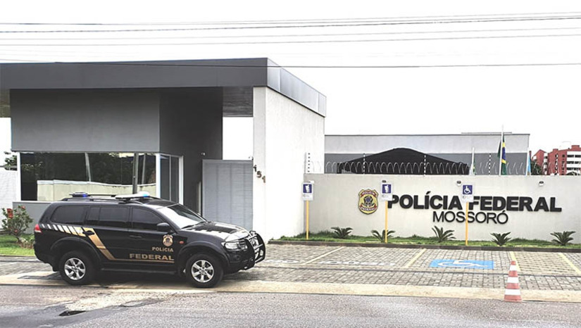 Imagem 1 -  Motorista de aplicativo é investigado por se passar por delegado da PF em Mossoró. Os policiais estão cumprindo um mandado de busca e apreensão expedido pela 10ª Vara da Justiça Federal/RN, em um endereço residencial no bairro Aeroporto. O investigado, um homem de 29 anos, responde a dois processos pela prática de crimes previstos no Estatuto do Desarmamento. A investigação teve início no mês de maio deste ano quando uma mulher procurou a Delegacia da PF em Mossoró para relatar que estaria sendo assediada por uma pessoa que teria se identificado como delegado da PF e que teria enviado credenciais de membro da instituição, após suposta interação ocorrida em um aplicativo de relacionamento.