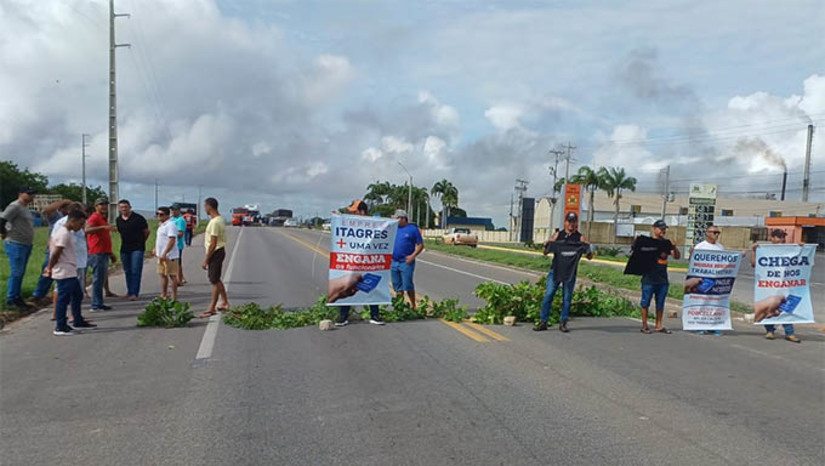 Imagem 1 - Os ex- funcionários da Itagrês Porcelanatti protestam contra a retirada silenciosa das maquinas da empresa e cobram o cumprimento de direitos trabalhistas. A Porcelanatti luta para manter uma suposta atividade fabril e assim, não correr o risco de perder o terreno de 120 mil metros quadrados situado no distrito industrial de Mossoró. O protesto bloqueou parte da BR 304, em frente a empresa, causando lentidão no trânsito. Imagem 1 - Os ex- funcionários da Itagrês Porcelanatti protestam contra a retirada silenciosa das maquinas da empresa e cobram o cumprimento de direitos trabalhistas. A Porcelanatti luta para manter uma suposta atividade fabril e assim, não correr o risco de perder o terreno de 120 mil metros quadrados situado no distrito industrial de Mossoró. O protesto bloqueou parte da BR 304, em frente a empresa, causando lentidão no trânsito.