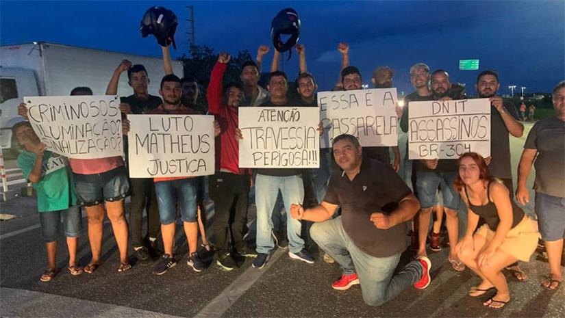 Imagem 1 -  População protesta devido a morte de motocicleta na BR-304 e pede construção de passarela no local. O protesto aconteceu na noite desta terça-feira (4), na altura do Sumaré, onde na noite desta segunda-feira (3), morreu vítima de um acidente de trânsito, o jovem Matheus Henrique Silva Oliveira, de 22 anos. A população pede a imediata retirada da faixa de pedestre, bem como de uma lombada instalada pouco antes dela. Para os moradores, apenas a construção de uma passarela poderá resolver o problema do local e garantir a segurança dos condutores, bem como dos pedestres que precisam atravessar a BR.