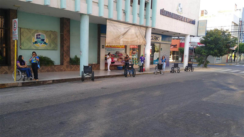 Imagem 1 -  Vereador “estaciona” cadeiras de rodas no Centro de Mossoró com recado: “É rapidinho, volto já”. O ato público, promovido pelo vereador Tony Fernandes, aconteceu na manhã desta segunda-feira (18) e teve como objetivo conscientizar a população sobre a necessidade de respeitar as vagas destinadas às pessoas com deficiência. “É rapidinho, volto já, essa frase é o que as pessoas com deficiência escutam em todo o país em relação as suas vagas de estacionamento”, explicou o vereador Tony. Panfletos educativos também foram entregues aos motoristas que passavam na rua em frente ao Poder Legislativo de Mossoró.