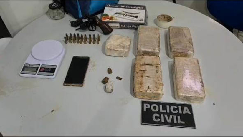 Imagem 1 -  Mulher é presa com cerca de 5kg de crack e uma arma de fogo, na Nova Mossoró. A prisão aconteceu nesta terça-feira (26). Durante as diligências decorrentes de uma investigação sobre o roubo de um aparelho celular, a polícia conseguiu localizar a residência onde o suspeito estava. Ao perceber a presença dos policiais, ele empreendeu fuga e pulou os muros de residências próximas, abandonando uma mochila que continha um revólver calibre 38, 18 munições do mesmo calibre, cerca de cinco quilos de crack, porções de maconha, uma balança de precisão e dois aparelhos celulares. Após recuperarem a mochila, os agentes retornaram à residência de origem e prenderam uma mulher que estava no local.