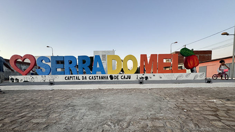 Imagem 1 -  Na tarde desta quarta-feira, 22, o prefeito Josivan Bibiano instalou na vila central do município, o nome Serra do Mel, em letras grandes, coloridas e iluminadas, acompanhado de um caju, simbolizando o principal fruto do município, considerado, em lei, a “Capital da Castanha de Caju” do RN. O letreiro também destaca o visionário José Cortez Pereira, que criou o município na década de setenta para ser o motor de desenvolvimento do Oeste do RN.